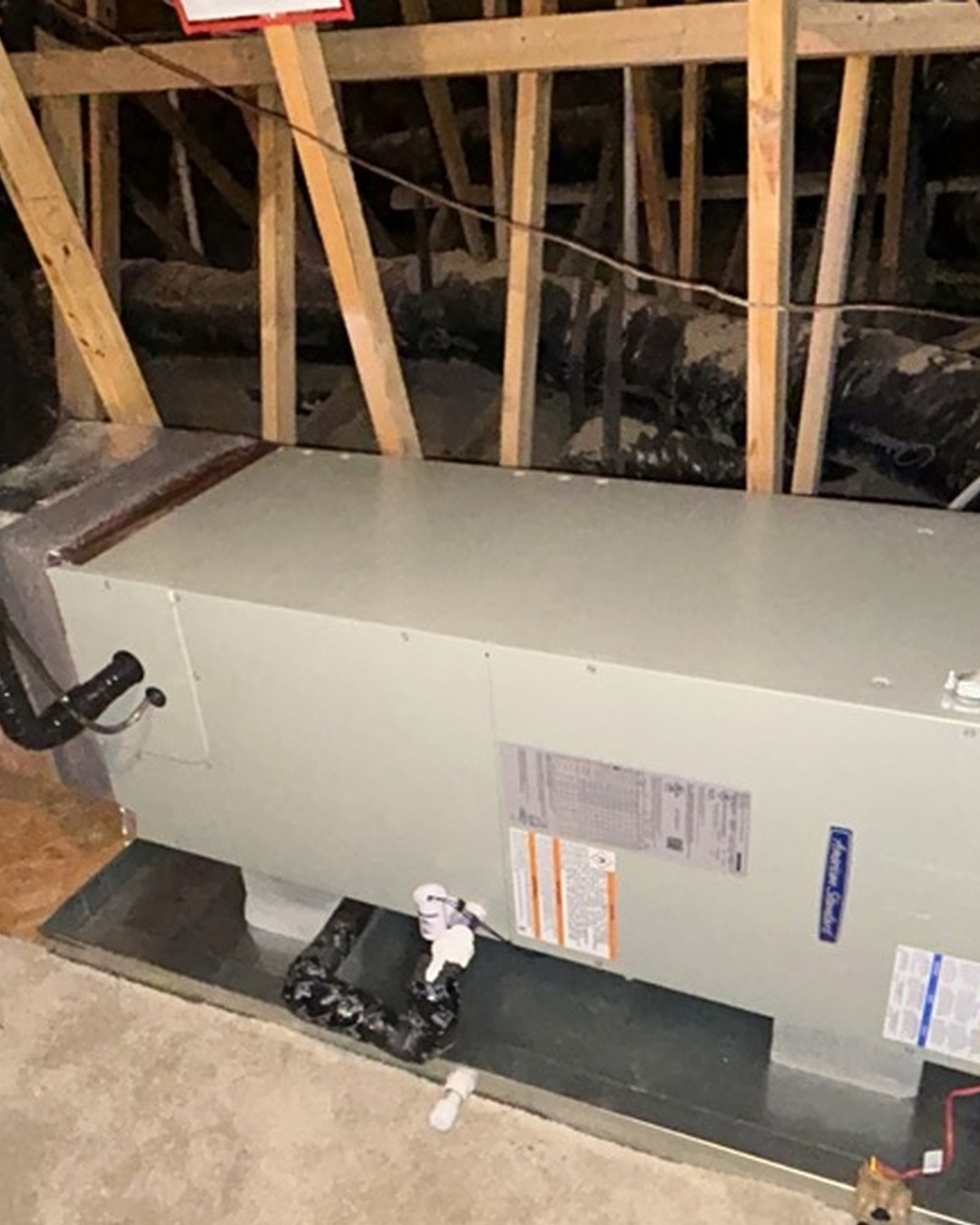 Jordan Heating & Air technician testing furnace flame sensor microamps with multimeter inside gas furnace burner assembly in Asheboro NC